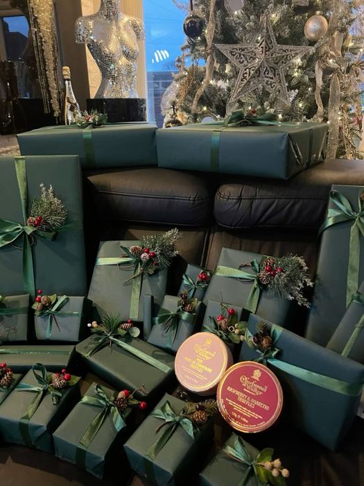 Cadeaux emballés en vert émeraude avec rubans satinés et pommes de pin